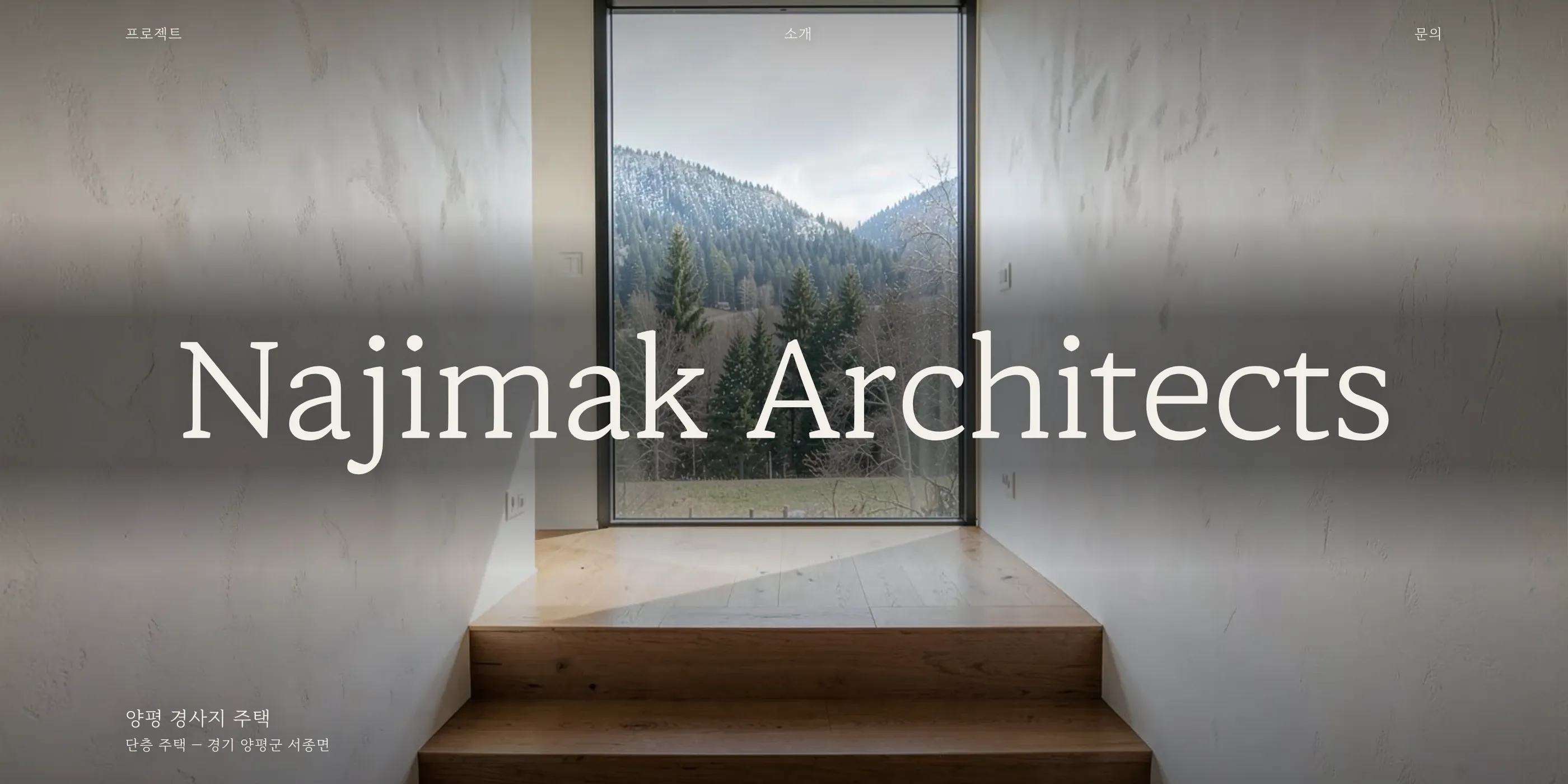데모 스튜디오 Najimak Architects 홈 첫 화면 — 창 너머 산이 보이는 실내 사진 위에 워드마크